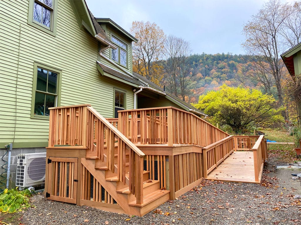 Newly built cedar deck with accessible ramp and railings on residential home in autumn - Barringer project by Cider House Integrity