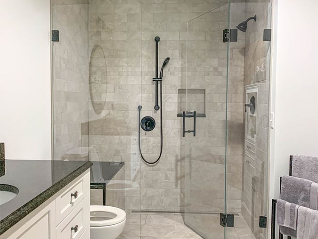 Curbless walk-in shower featuring frameless glass door, matte black fixtures, rainfall showerhead, and built-in niche