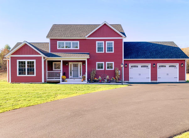 Modern two-story commercial building with gray metal siding, large glass storefront windows, white trim accents, double entry doors with awnings, and parking area in front