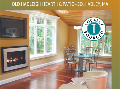 Cozy contemporary interior featuring gas fireplace, wall-mounted television, vaulted ceiling, abundant natural light from multiple windows, round dining area, and beige armchair