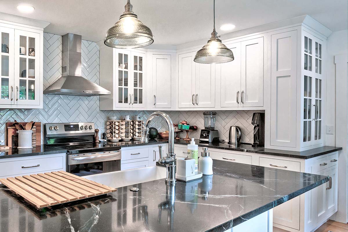 Bright farmhouse kitchen renovation in Pelham, Massachusetts with custom white cabinetry, quartz countertops, stainless steel appliances, and a large center island.