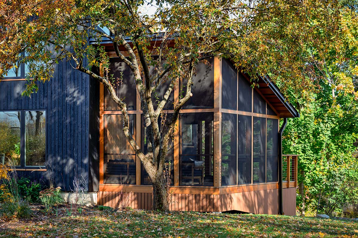 Modern accessory dwelling unit (ADU) with black vertical siding, screened porch, and warm wood accents, custom built in Amherst, Massachusetts.